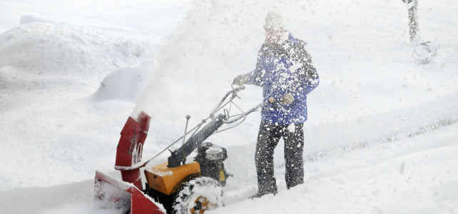 Man is making a path by removing snow with snow blower